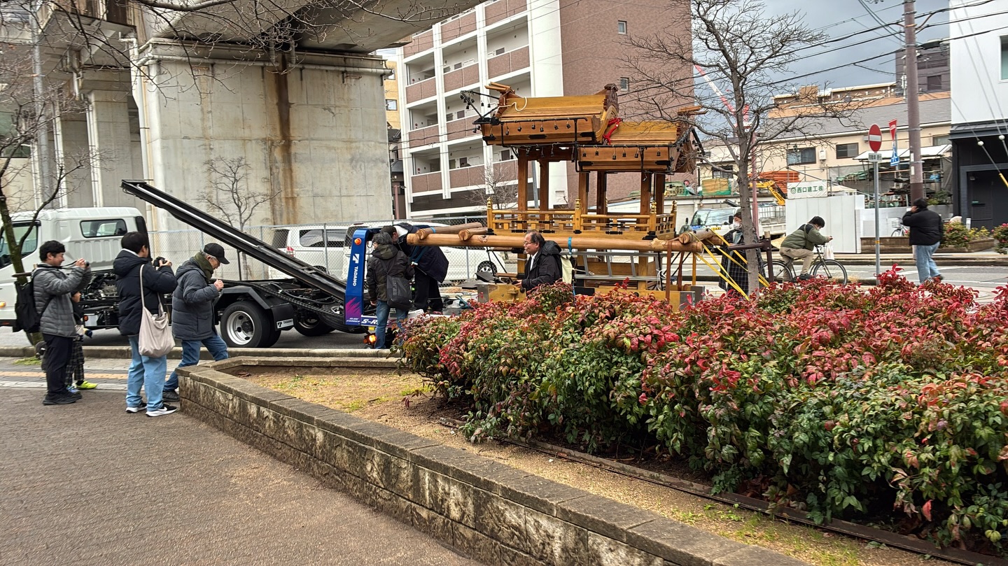 高架下でクレーン車から木製のだんじりが吊り降ろされている